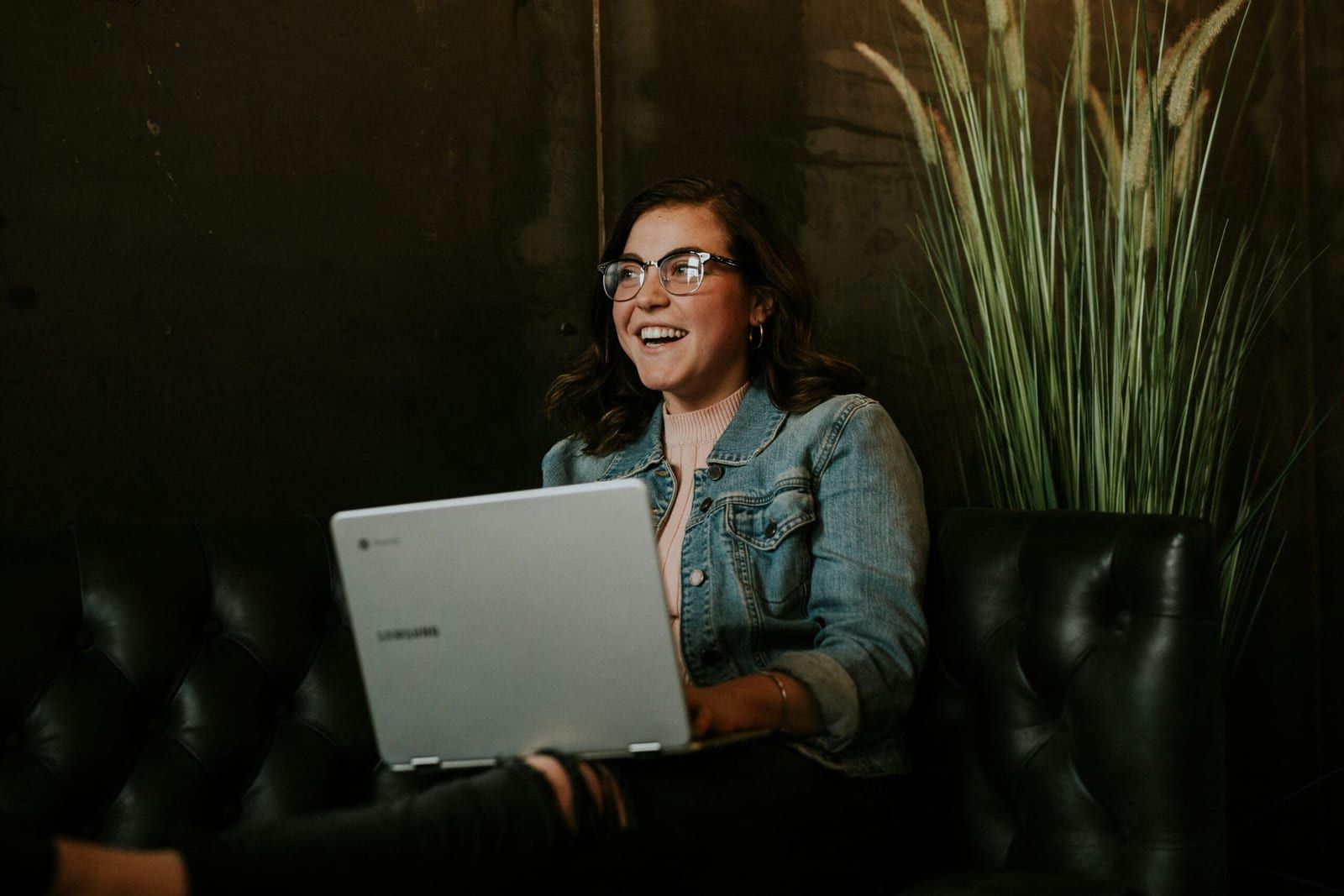 A smiling woman studies on a laptop in a quiet room