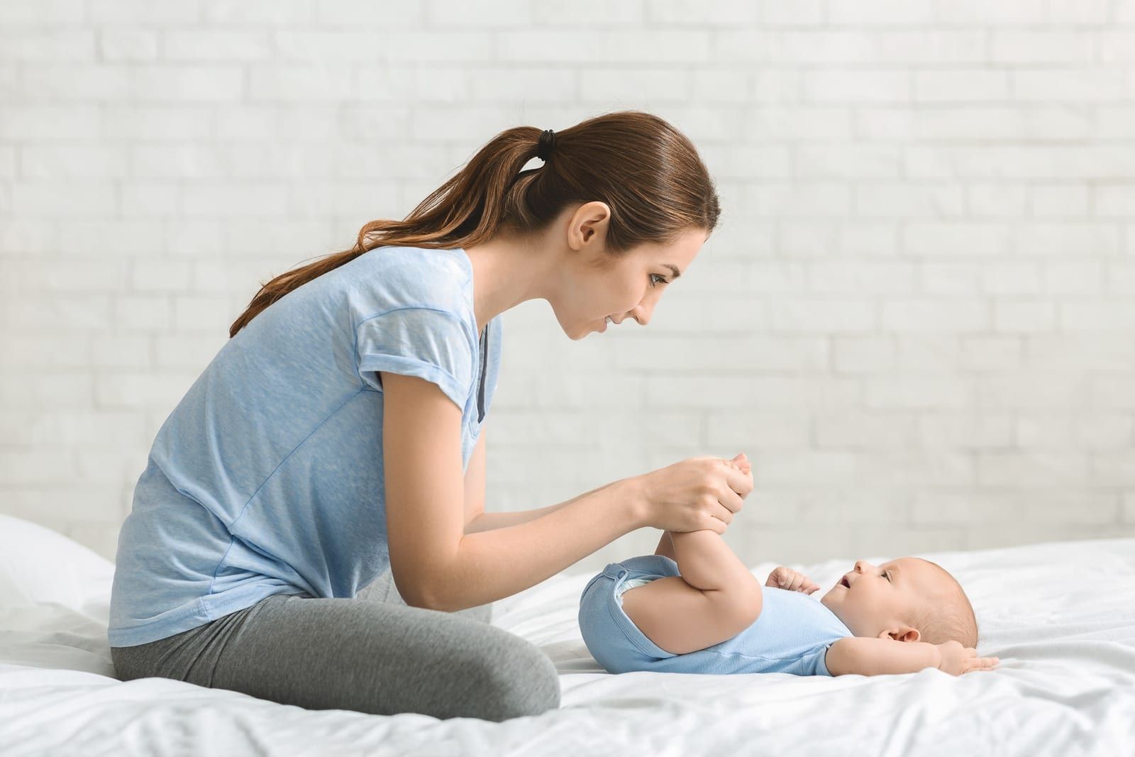A caregiver gently massages a newborn on a bed