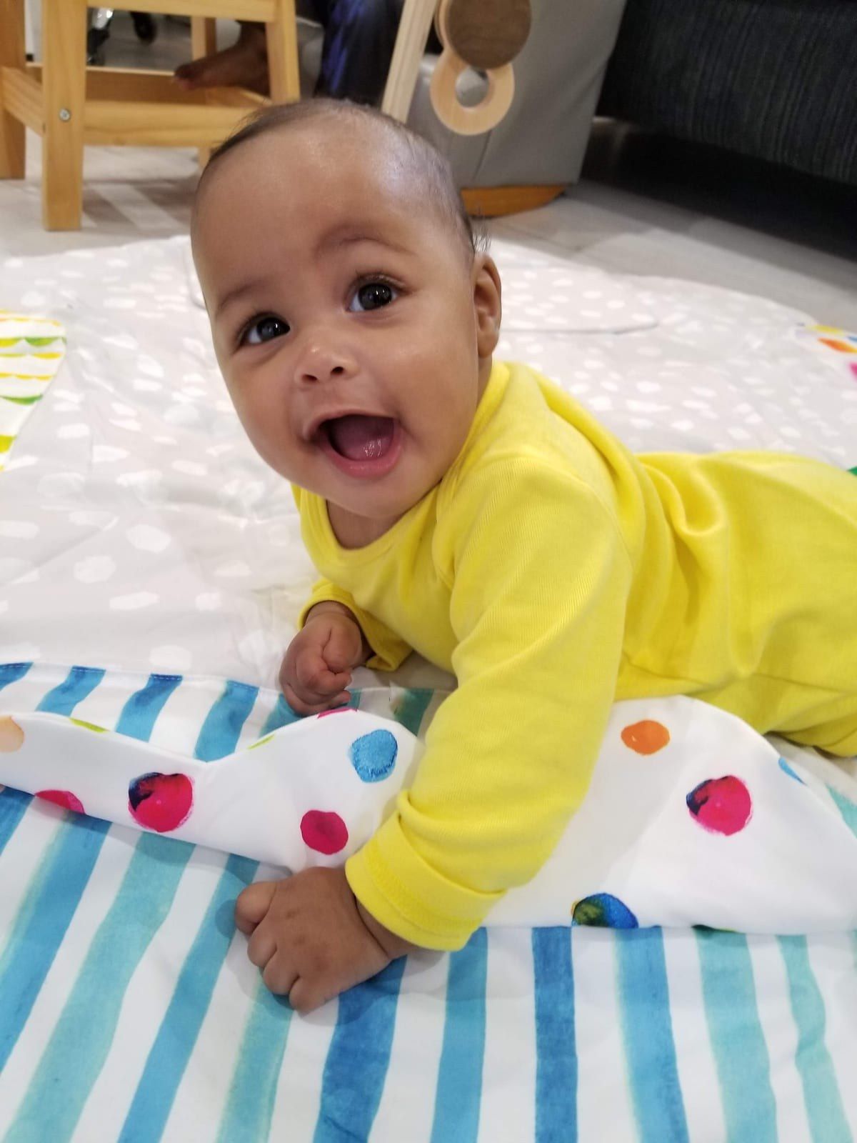 A baby lifts their head and smiles during tummy time