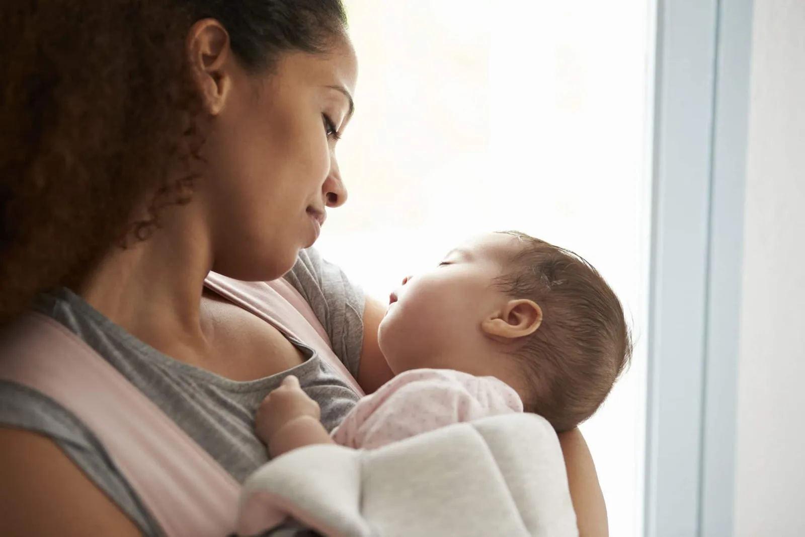 Close Up Of Nanny Cuddling Baby Daughter At Home