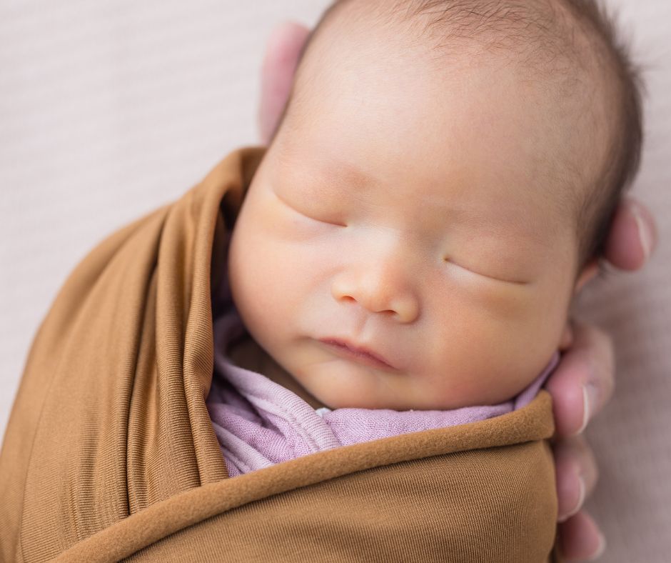 A swaddled newborn resting with closed eyes